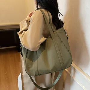 Macro detail of olive green nylon tote bag with reinforced handles and silver metal hardware