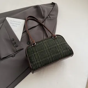 Detail of vintage green plaid tweed Boston bag with leather handles on a grey blazer