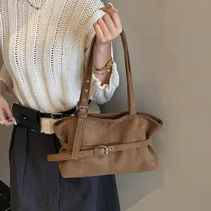 Detailed view of the brown suede tote bag featuring a metallic buckle and grommet belt strap