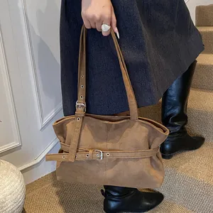 Detail view of brown suede tote bag with adjustable belt buckle and dual shoulder straps