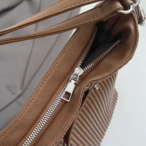 Close-up of brown lychee grain leather handbag with silver zipper and pleated side detail