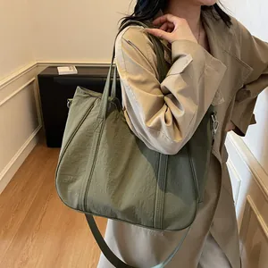 Detail of olive green nylon tote bag showing its pleated texture and adjustable strap