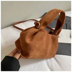 Detail of vintage brown suede handbag showing overlapping handle design and gold D-ring hardware
