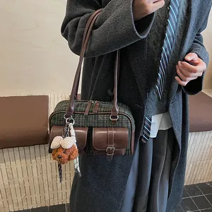 Detail of vintage plaid shoulder bag with front flap pockets and cute teddy bear charm