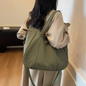 Side view of a dark green large capacity nylon tote bag worn by a model for daily use