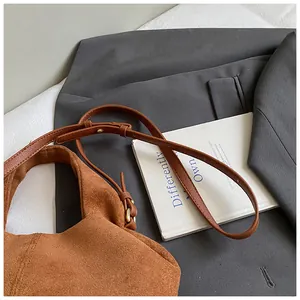 Detail view of brown suede hobo bag with smooth leather strap and gold metal buckle