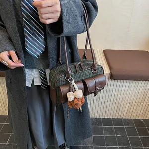 Close-up of retro plaid Boston bag with leather trim and a cute plush dog charm detail