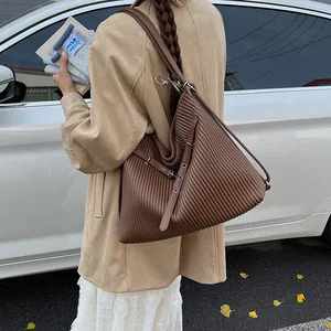 Detail of the vertical pleated texture and silver buckle on a dark brown tote bag