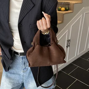 Detailed view of brown suede handbag with soft pleats and thin shoulder strap
