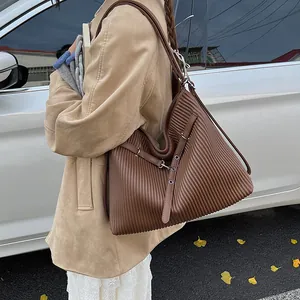 Detail of brown pleated tote bag featuring vertical accordion folds and silver buckles