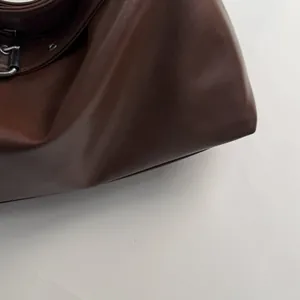 Detailed macro view of dark brown matte leather texture and silver D-ring buckle