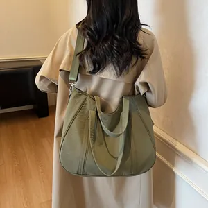 Detailed view of olive green large tote bag worn on shoulder over a beige coat