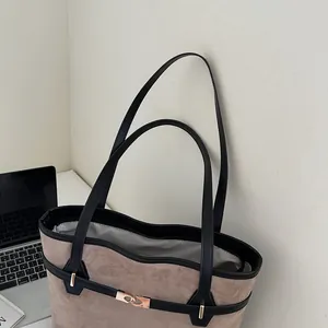 Détail d'un sac cabas en daim kaki avec fines anses noires et boucle dorée élégante