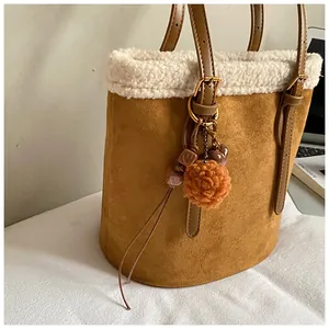 Detail der braunen Wildleder-Beuteltasche mit weißem Fleece-Besatz und Anhänger