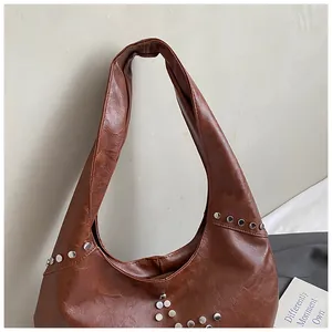 Detail of a brown retro oil leather tote bag featuring stylish silver metal rivets