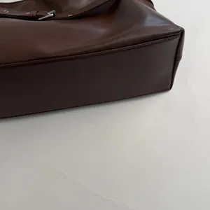 Detailed macro view of dark brown leather tote bag with silver metal buckle and stitching
