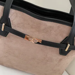 Gros plan détaillé du sac en daim beige et cuir noir avec boucle métallique dorée élégante
