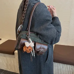 Detail view of a green plaid Boston bag with a cute teddy bear charm on wool coat