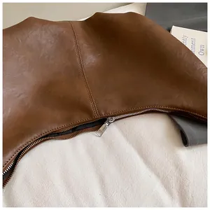 Détail du sac croissant en cuir marron avec fermeture éclair argentée et coutures