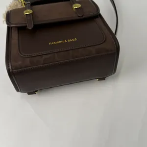 Détail du sac à main en cuir marron foncé avec ferrures dorées et logo gravé