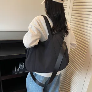 Detail view of large capacity black nylon shoulder bag showing wide strap and sleek finish