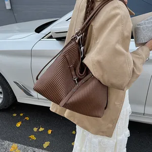 Detail of a large brown pleated tote bag with metal hardware and soft PU leather texture
