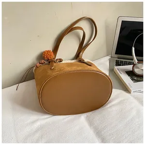 Detail der karamellfarbenen Wildleder-Beuteltasche mit Plüschbesatz und Quasten-Anhänger