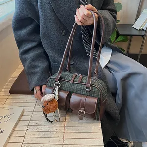 Close-up of retro green plaid Boston bag with brown leather pockets and a cute teddy charm