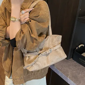 Close-up of vintage brown suede tote bag featuring a leather belt buckle and silver metal hardware