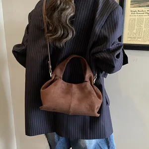 Detail of brown suede crossbody bag showing the matte texture and soft crescent shape