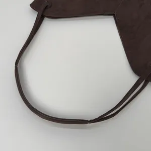 Détail du sac cabas en daim marron foncé avec fines bandoulières et œillets en métal