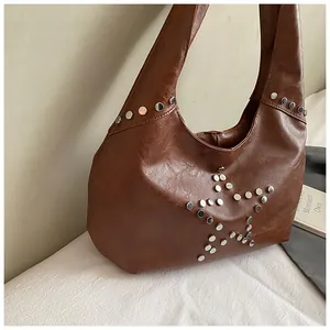 Macro detail of silver studs forming a star pattern on brown faux leather hobo bag