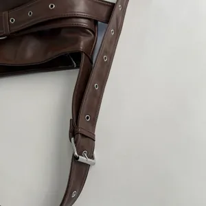 Close-up of brown leather shoulder strap with silver metal eyelets and adjustable buckle