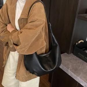 Détail d'un sac hobo noir en cuir porté avec une veste en daim marron élégante