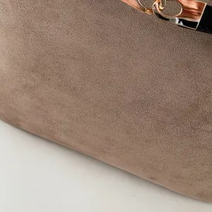 Gros plan sur la texture du daim marron du sac cabas avec boucle élégante en or rose