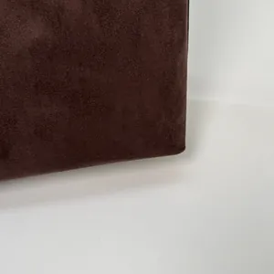 Détail macro de la texture en daim marron mat et coutures d'angle du sac fourre-tout