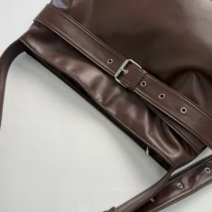Close-up of vintage dark brown faux leather bag with silver metal eyelet buckle details