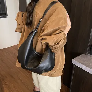 Détail du sac hobo noir minimaliste en similicuir souple avec plis et fermeture éclair