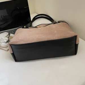 Détail d'un grand sac cabas en daim marron et cuir noir dans un décor de bureau moderne
