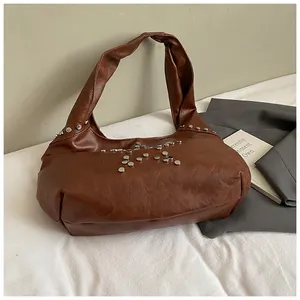 Close-up of brown faux leather shoulder bag featuring silver metal star rivet detailing