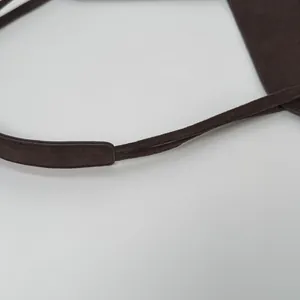 Détail de la bandoulière de sac en daim marron foncé montrant les coutures et la texture