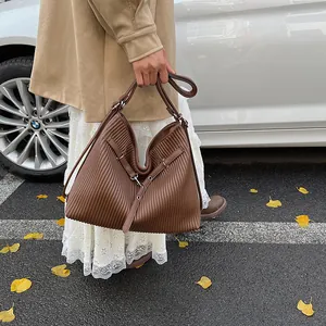 Detail view of large brown tote bag featuring vertical pleats and silver metal hardware