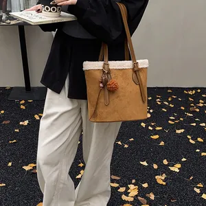 Detail der Wildleder-Beuteltasche mit weißem Lammfellbesatz und Plüsch-Pompon-Anhänger