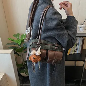 Detail of green plaid tweed Boston bag with leather pockets and brown puppy pendant charm