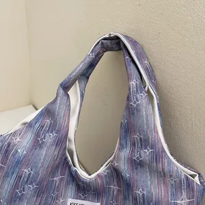 Detail of gradient stripe tote bag featuring white star patterns and woven logo label