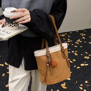 Details einer braunen Wildleder-Beuteltasche mit weißem Pelzbesatz und Herzanhänger
