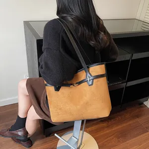 Détail du grand sac cabas en daim marron avec bordure en cuir noir et boucle dorée