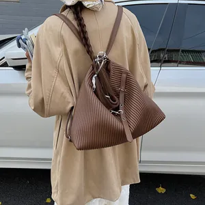 Detail of dark brown pleated texture and leather buckle on a casual backpack