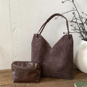 Détail du sac cabas mat marron foncé avec pochette assortie sur une surface en bois