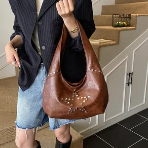 Close-up of brown vintage underarm bag with decorative metal star studs on premium leather